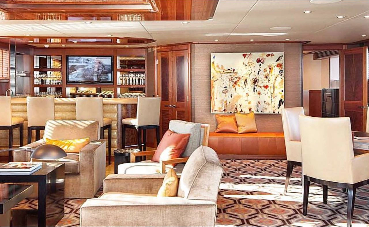 Monarch's wood-panelled Skylounge with a bar, cream seating and orange upholstery.