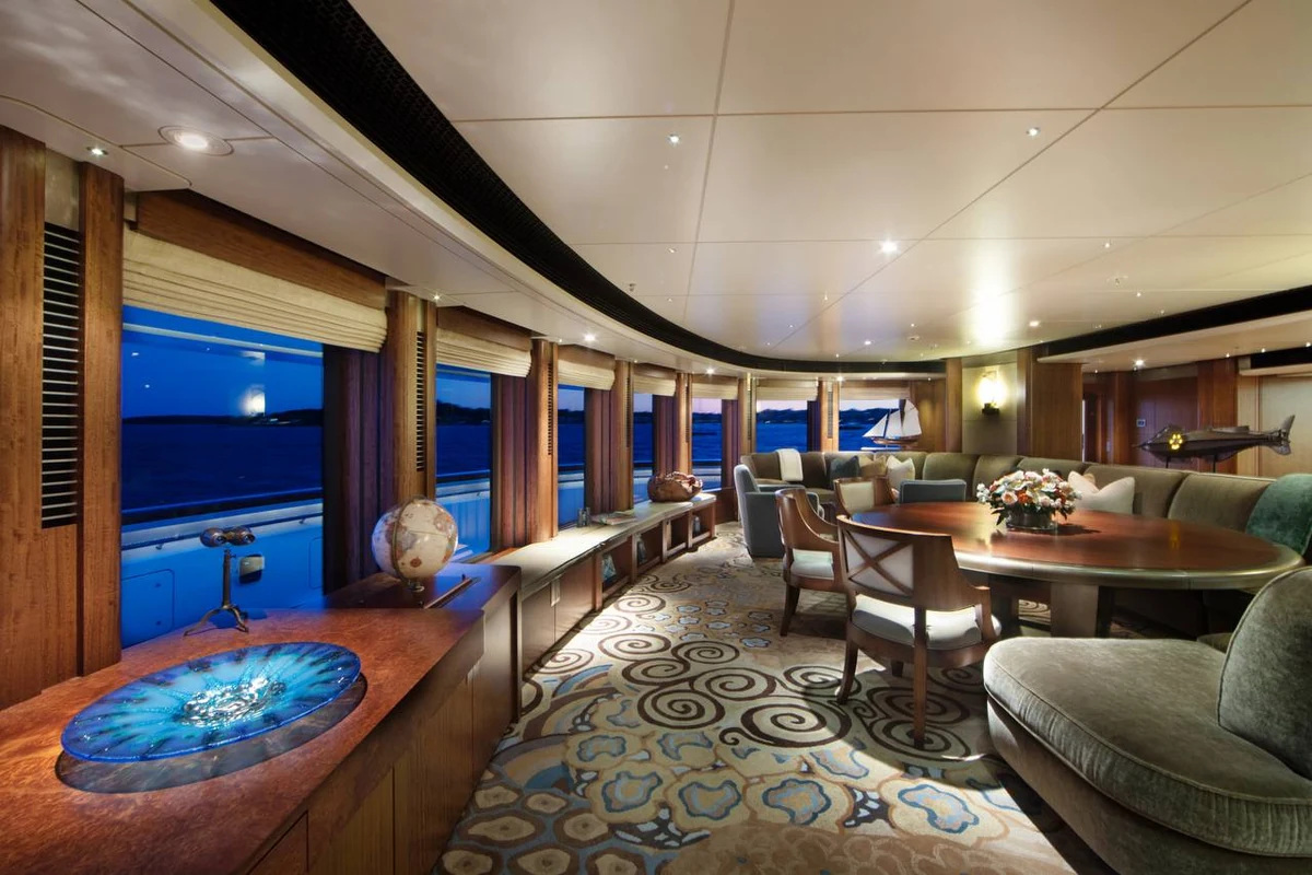 Octopus lounge at dusk with curved windows, a round dining table and patterned carpet
