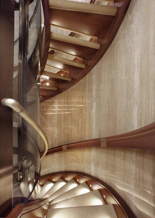 Silver Shalis curved staircase with timber treads, bronze handrails and textured stone walls.