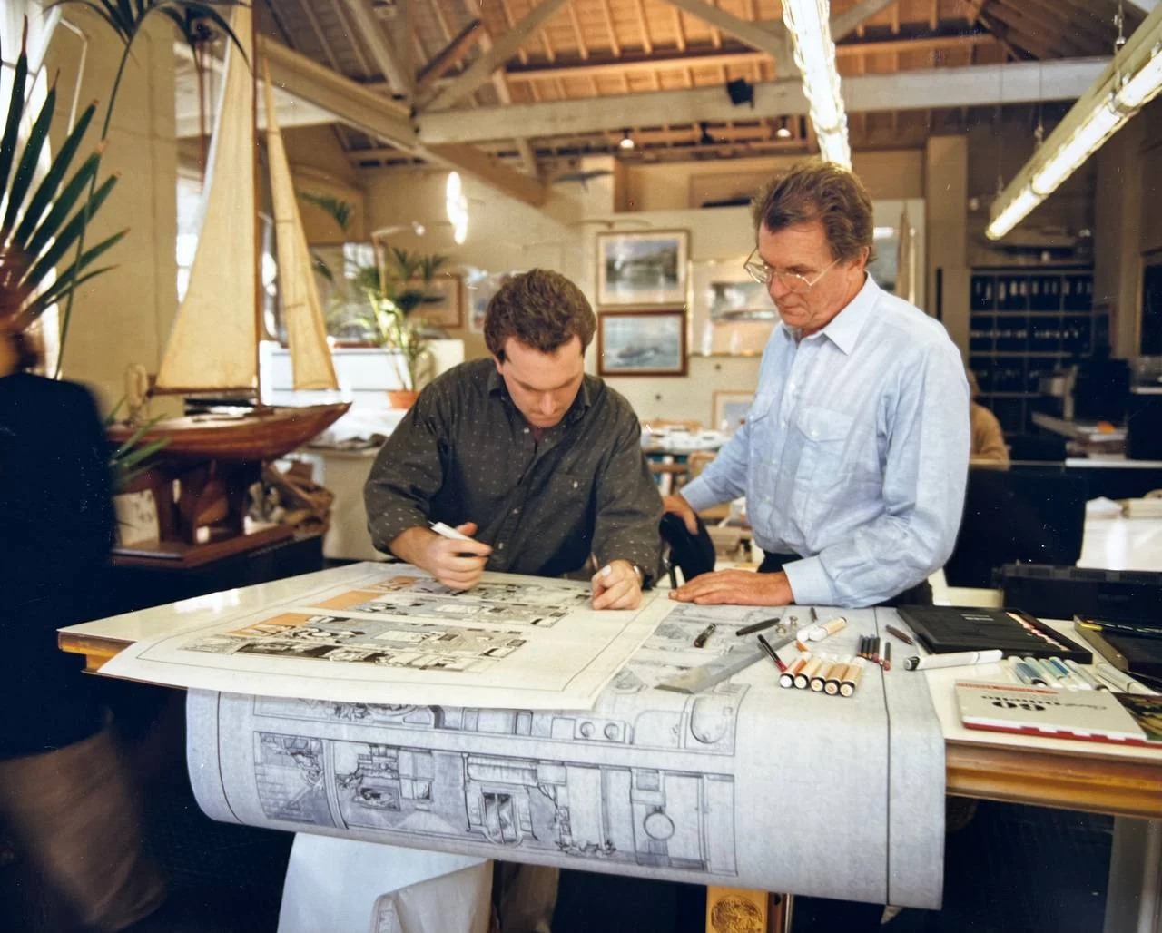 Jonathan Quinn Barnett at the drawing board with Jon Bannenberg looking on, Burnsall Street studio, London, early 1990s